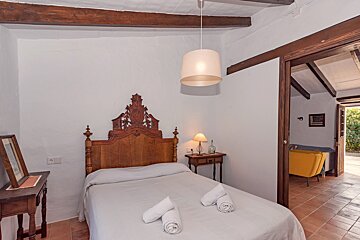 A bedroom with a bed and a lamp hanging from the ceiling
