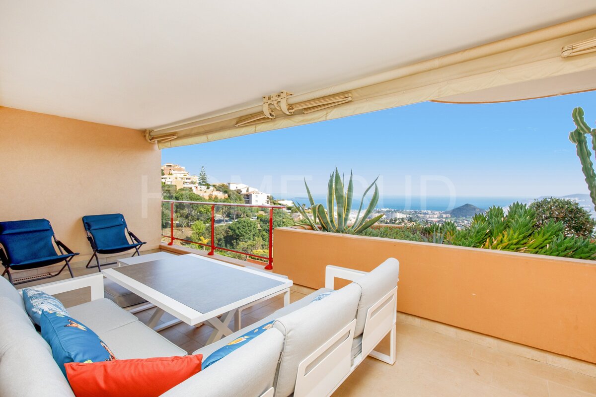 A balcony with a couch and chairs and a view of the ocean
