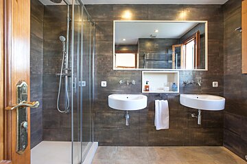 A bathroom with two sinks and a walk in shower