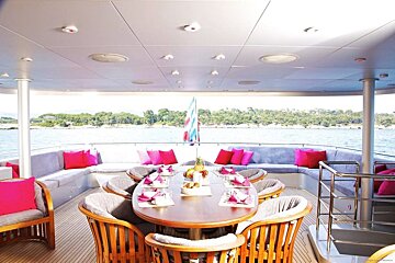 A dining area on a boat with a table and chairs