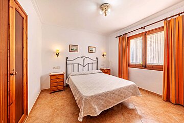 A bedroom with a white bed and orange curtains