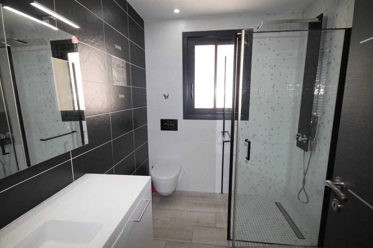 A bathroom with black and white tiles and a walk in shower