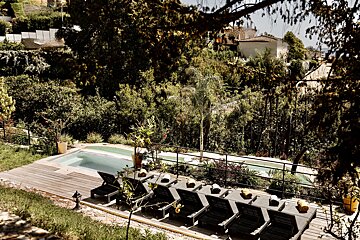 A row of black lounge chairs sit in front of a swimming pool