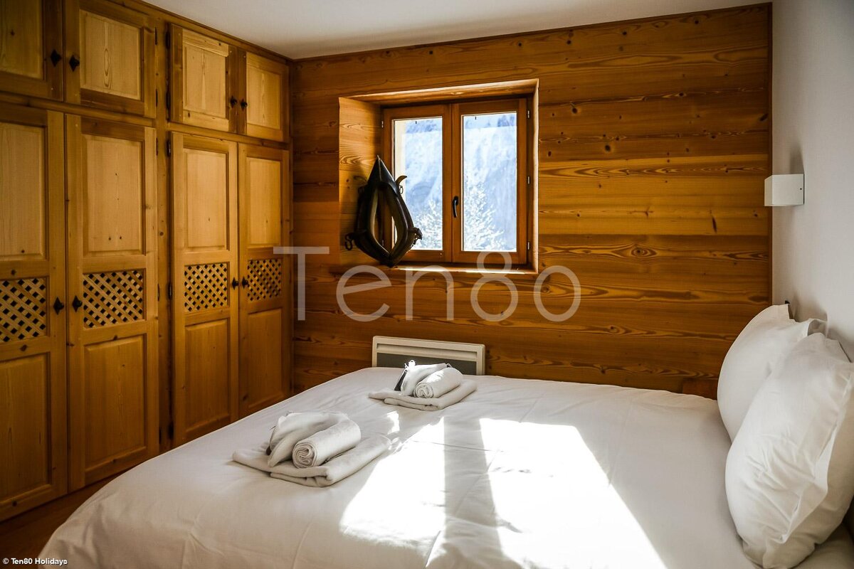 A bedroom with a bed and a window with the word tenoo on the wall