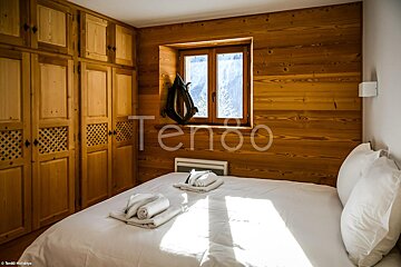 A bedroom with a bed and a window with the word tenoo on the wall
