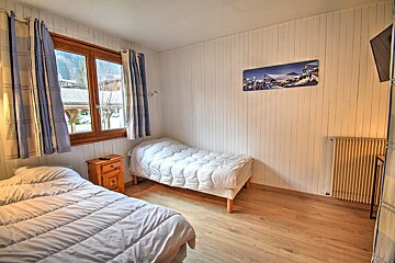 A bedroom with two beds and a picture of skiers on the wall