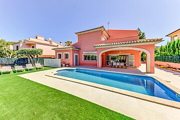 A pink house with a large swimming pool in front of it