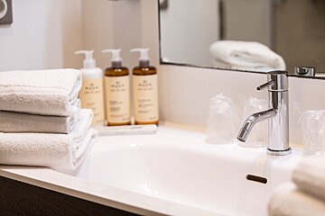 A bathroom sink with bottles of nuxe on the counter