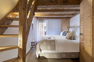 A bedroom with a wooden staircase leading up to the second floor
