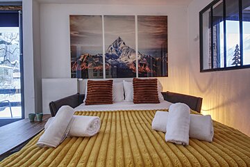 A bed with a picture of a mountain on the wall above it
