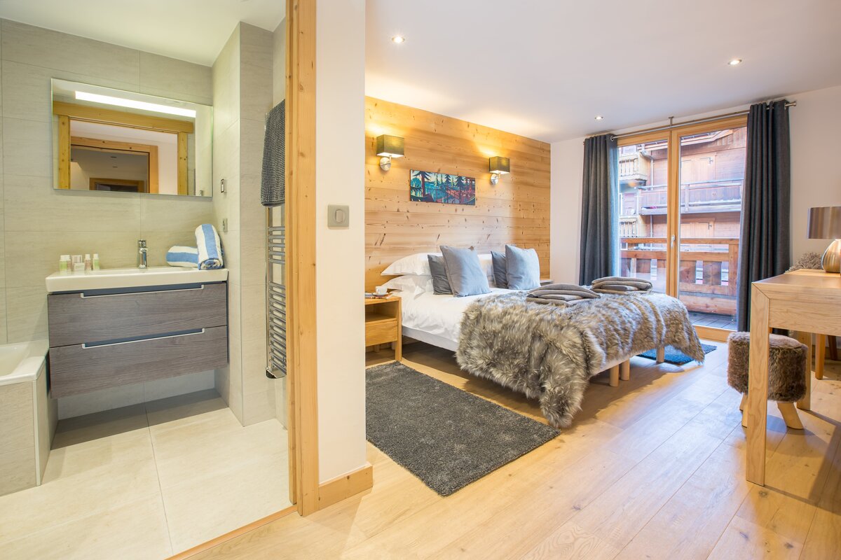 A bedroom with a bed and a bathroom behind it