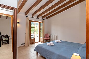 A bedroom with a blue bed and wooden beams on the ceiling