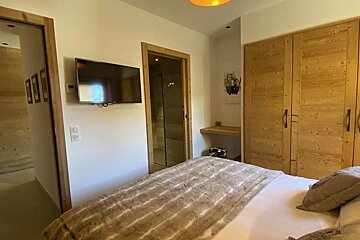 A bedroom with a large bed and a flat screen tv