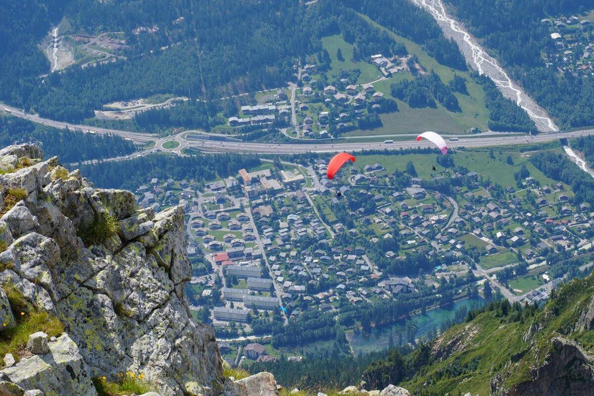 A paraglider is flying over a small town in the mountains
