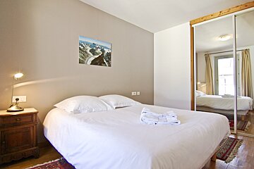 A bedroom with a painting on the wall above the bed