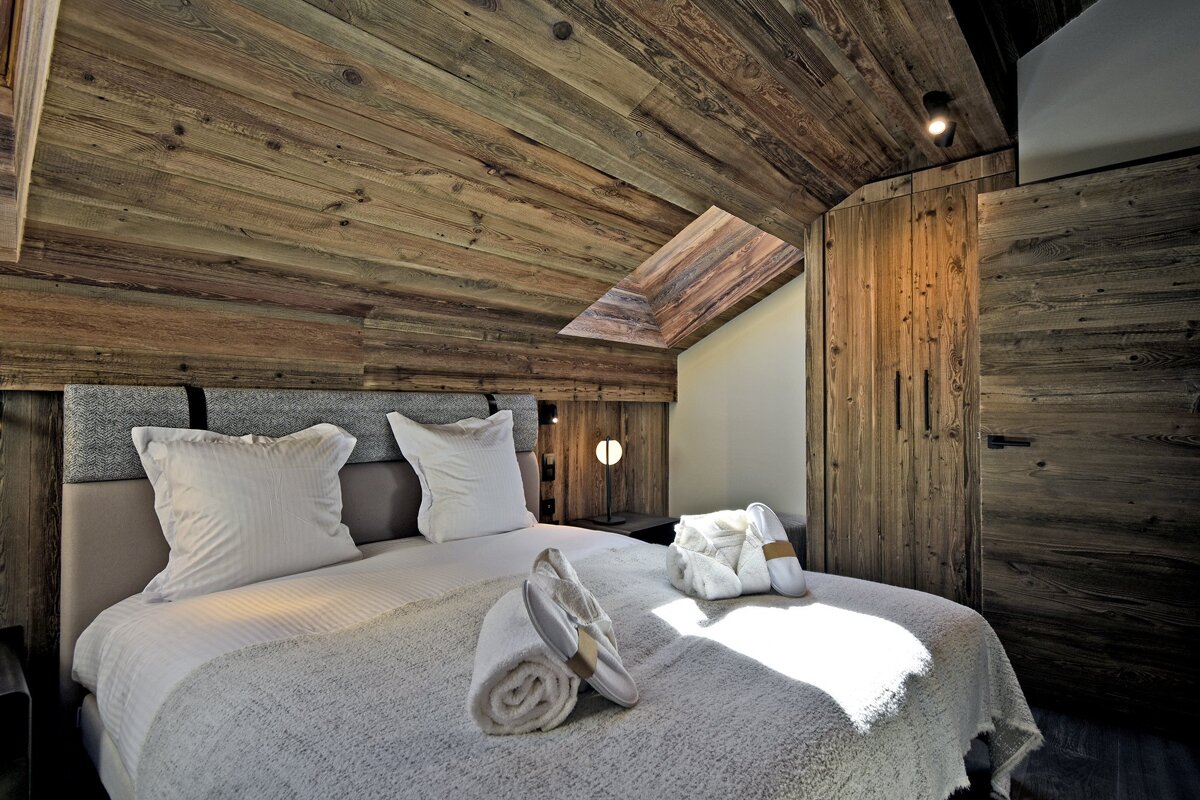 A bedroom with a wooden ceiling and a bed
