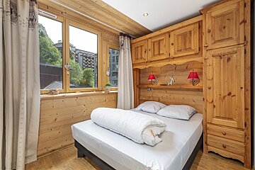 A wooden bedroom with a bed and a window