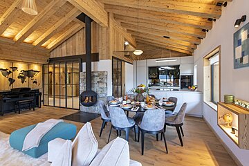 A living room with a dining table and chairs and a piano