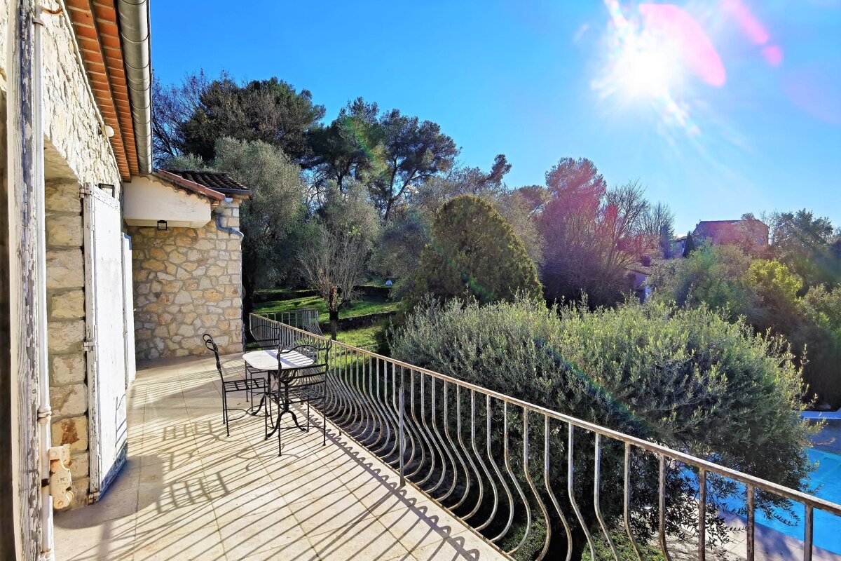 A balcony with a table and chairs and trees in the background