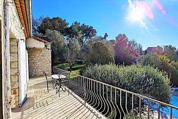 A balcony with a table and chairs and trees in the background