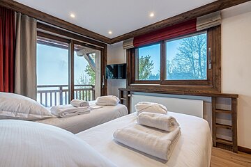 A bedroom with two beds and a television on the wall