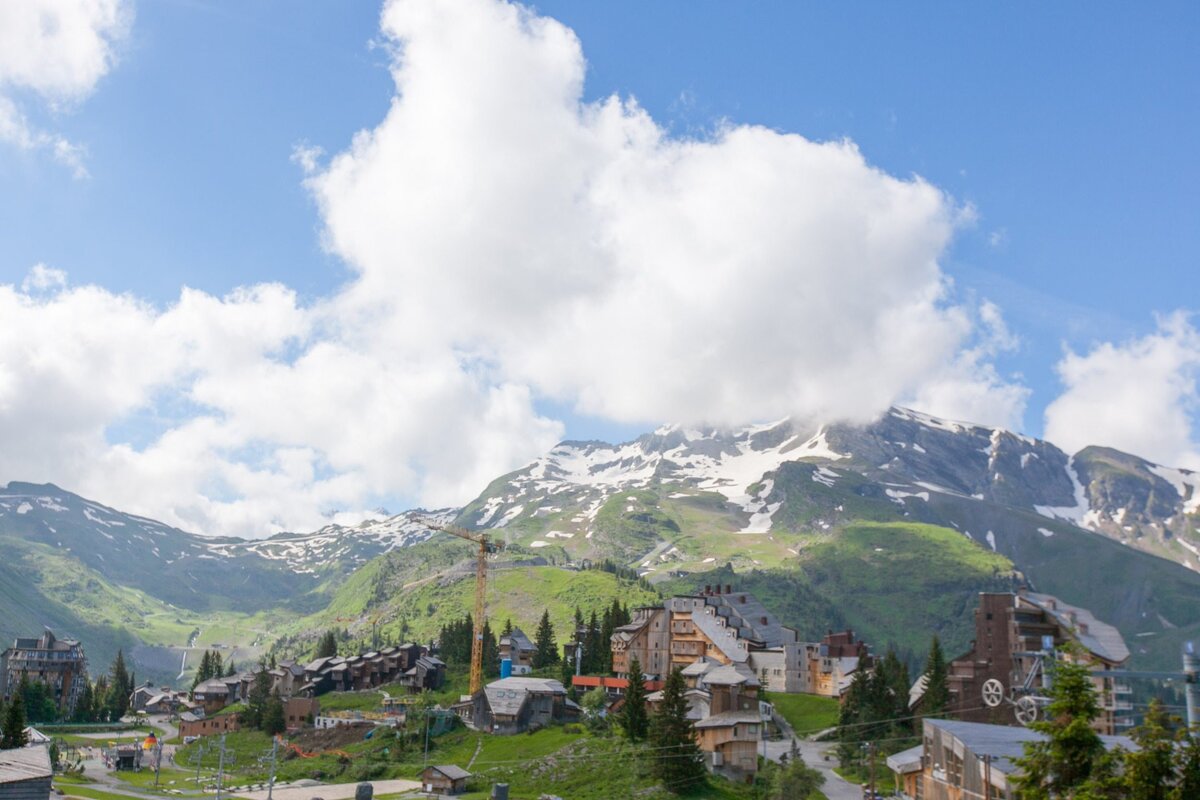 A mountain covered in snow with a few buildings in the foreground
