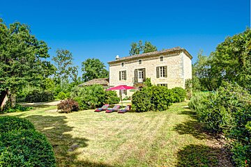A large stone house with a pink umbrella in front of it
