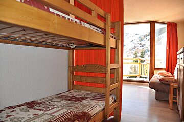 A bunk bed with a red curtain behind it