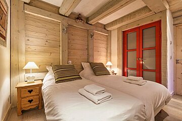 A bedroom with two beds and a red door