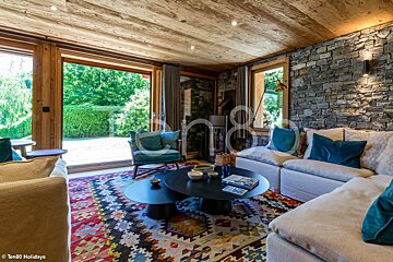 A living room with a colorful rug and a couch and chairs and a table