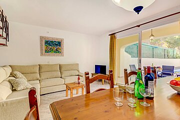 A bottle of merlot sits on a wooden table in a living room