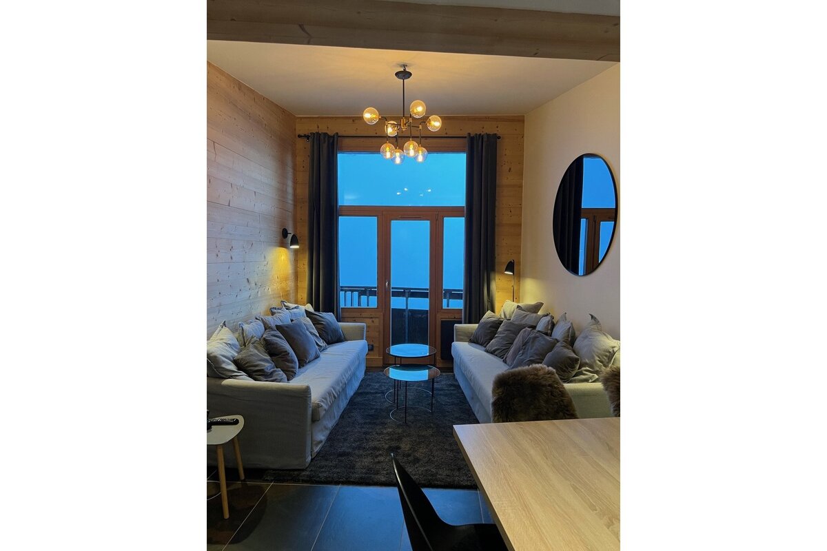 A living room with two couches and a round mirror