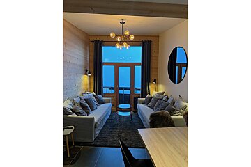 A living room with two couches and a round mirror