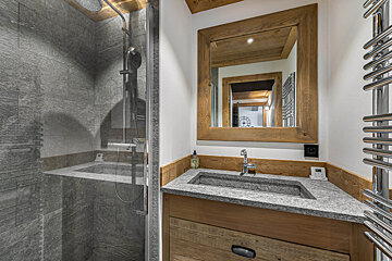 A bathroom with gray tiles and a shower head