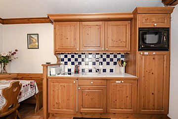 A small kitchen with wooden cabinets and a microwave