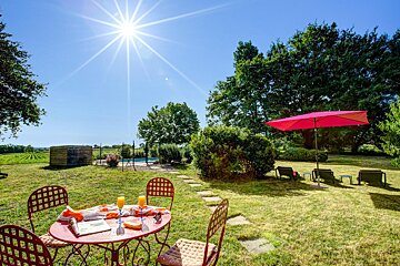 A lawn with a table and chairs and a pink umbrella
