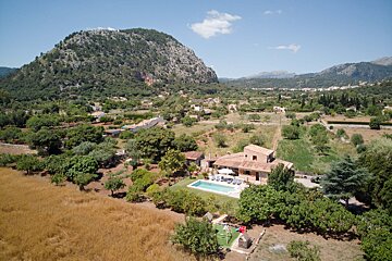 An aerial view of a house with a large pool in front of a mountain