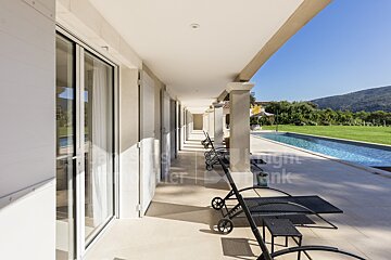 A patio with chairs and a swimming pool in the background