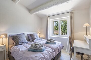 A bedroom with two beds a desk and a window