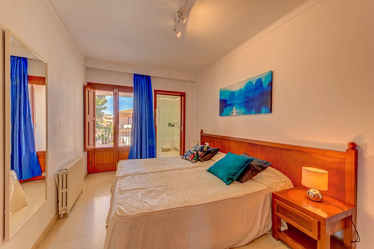 A bedroom with a painting on the wall above the bed