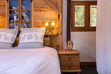A bedroom with a bed and a nightstand with a candle on it