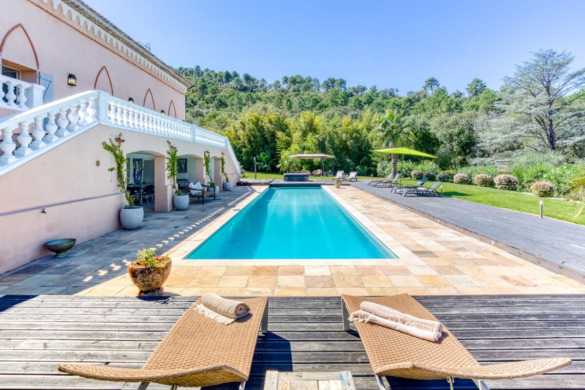 A large swimming pool is surrounded by chairs and umbrellas