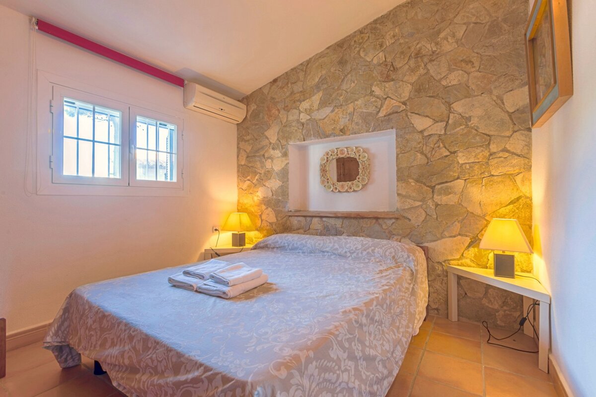 A bedroom with a stone wall and a bed