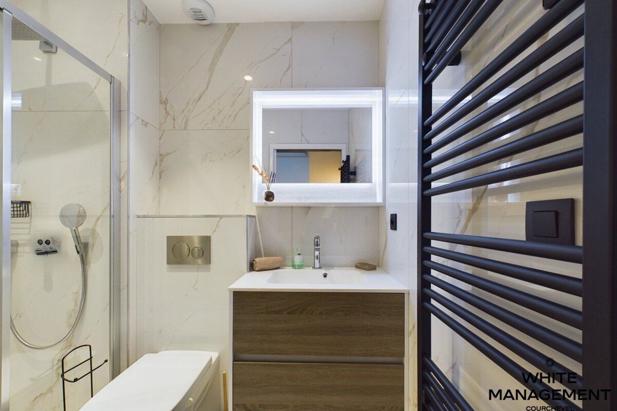 A bathroom with a shower and a black towel rack