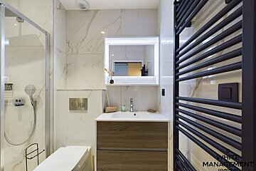 A bathroom with a shower and a black towel rack