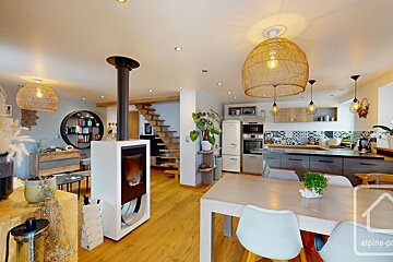 Spacious open-concept living, dining, and kitchen with a stylish fireplace, wooden floors, and woven light fixtures. A modern yet cozy home.