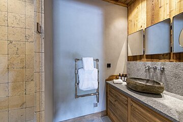 A bathroom with a stone sink and two mirrors
