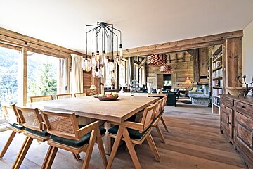 A dining room with a large wooden table and chairs