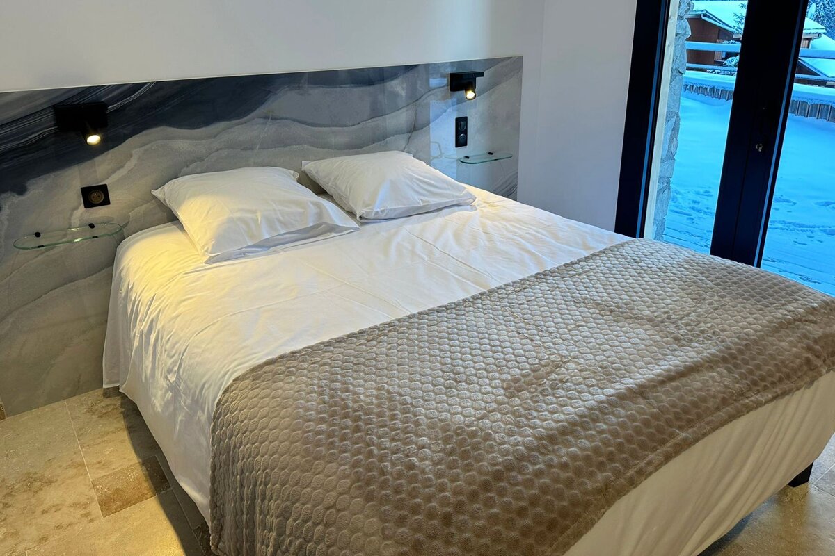 A bed with white sheets and a brown blanket