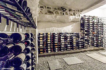 Bottles of wine are lined up in a wine cellar